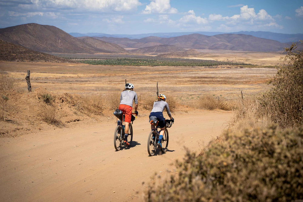 Shows two cyclists on a desert track with mountains in the background, showcasing Litebike lightweight bike cassettes, stems and seatpost